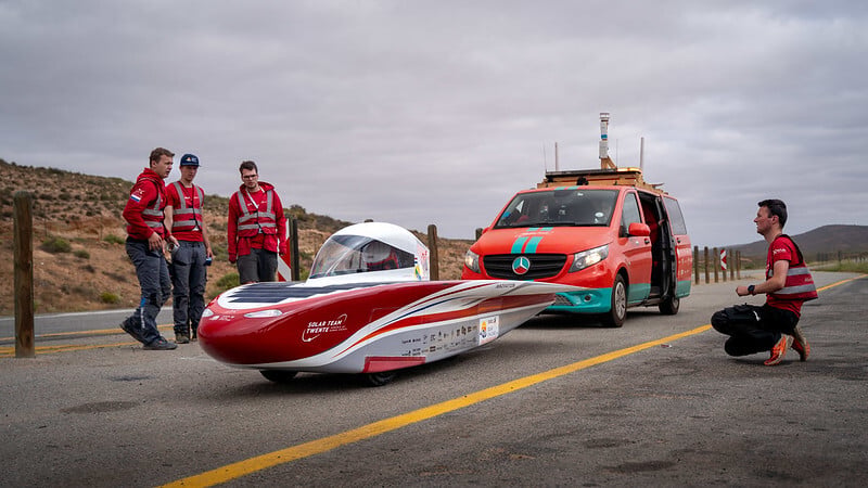 A group of drivers standing around the solar team twente vehicle